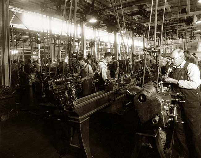 Una vieja foto en blanco y negro de una antigua fábrica y sus trabajadores.