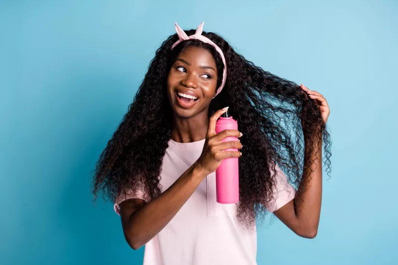 Foto de una mujer usando un producto en aerosol en su cabello largo