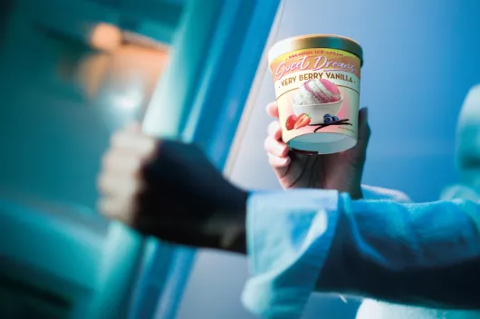 Mano en el congelador sosteniendo una caja de helado de papel